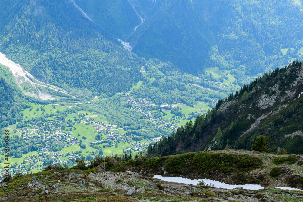 The town of Les Houches surrounded by green mountains in the Mont Blanc massif in Europe, France, the Alps, towards Chamonix, in summer, on a sunny day.