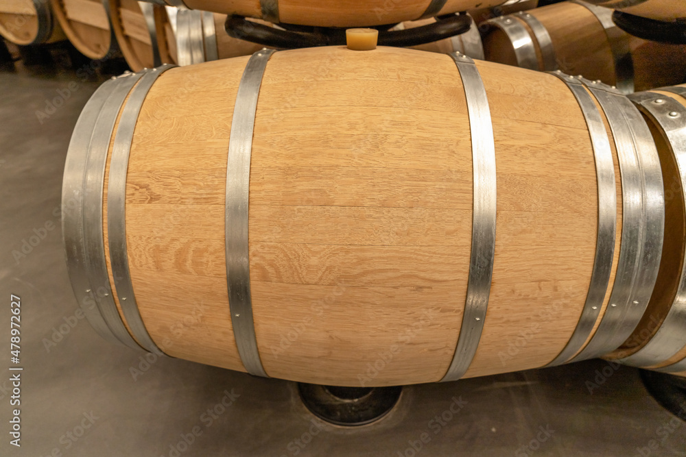 Yellow oak barrel with stainless steel rings at a winery for making wine. Side view. Advertising space, copy space Yellow oak barrel with stainless steel rings at a winery for making wine. Side view. Advertising space, copy space