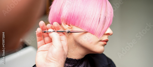 Tablou pe pânză Hand of a hairdresser cutting short pink with scissor hair in a hairdressing sal