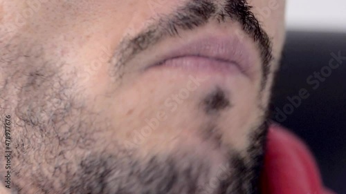 Close up of the mouth of a young bearded man while chewing bubble gum photo