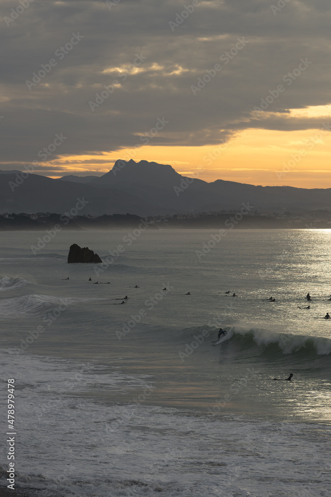 Surfer silhouette surfing a wave in Bidart with a mountain layouts in the background- Les landes - France