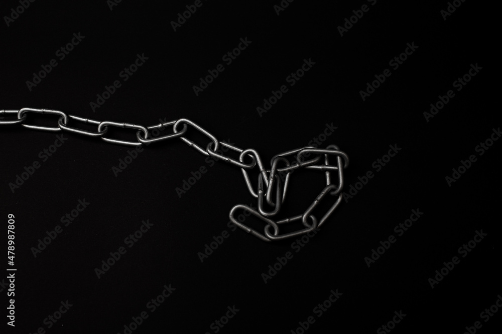 Large gray metal chain lies on a black background