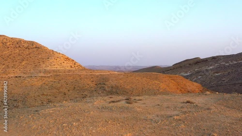 Aerial Forward Shot Of Rock Formations In Brown Desert Against Clear Sky - Dimona, Israel photo