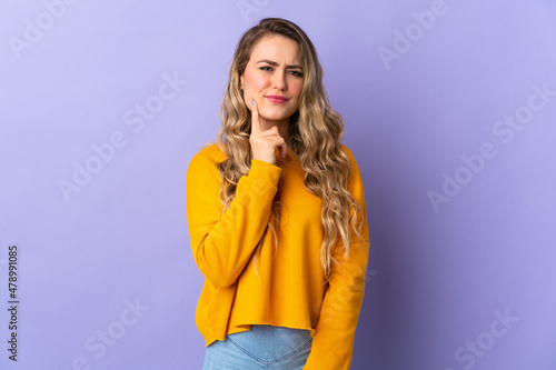 Young Brazilian woman isolated on purple background and thinking © luismolinero