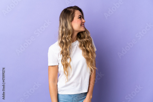 Young Brazilian woman isolated on purple background looking to the side and smiling
