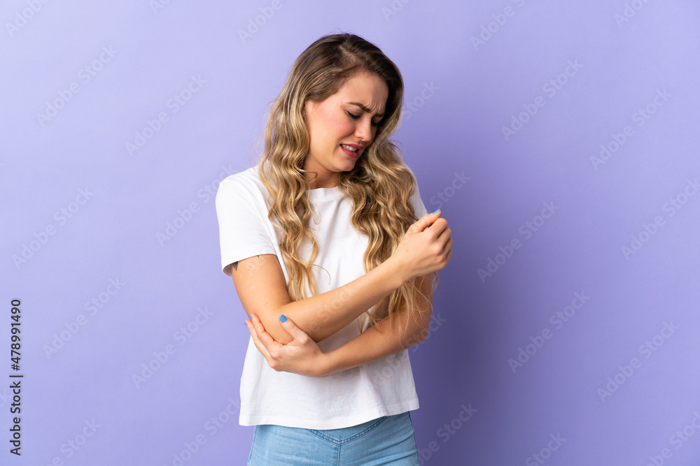 Young Brazilian woman isolated on purple background with pain in elbow Young Brazilian woman isolated on purple background with pain in elbow