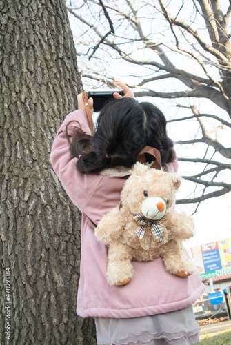 木の写真を撮る女の子の後ろ姿 縦写真