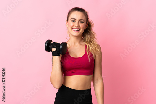 Young Brazilian woman isolated on pink background making weightlifting