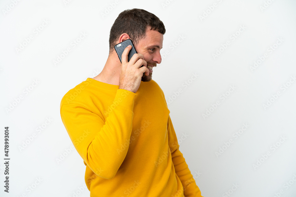 Young Brazilian man isolated on white background keeping a conversation with the mobile phone with someone Young Brazilian man isolated on white background keeping a conversation with the mobile phone with someone