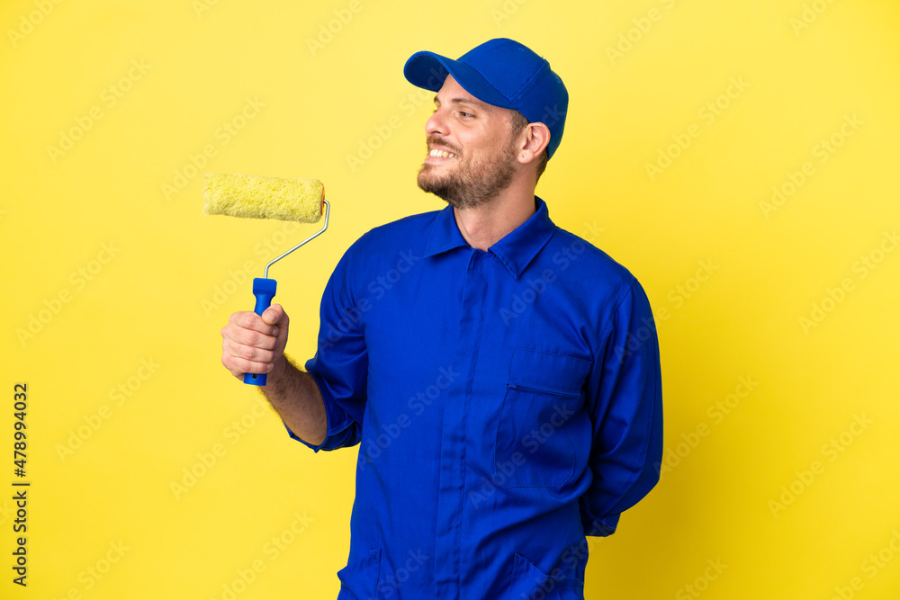 Painter Brazilian man isolated on yellow background looking side