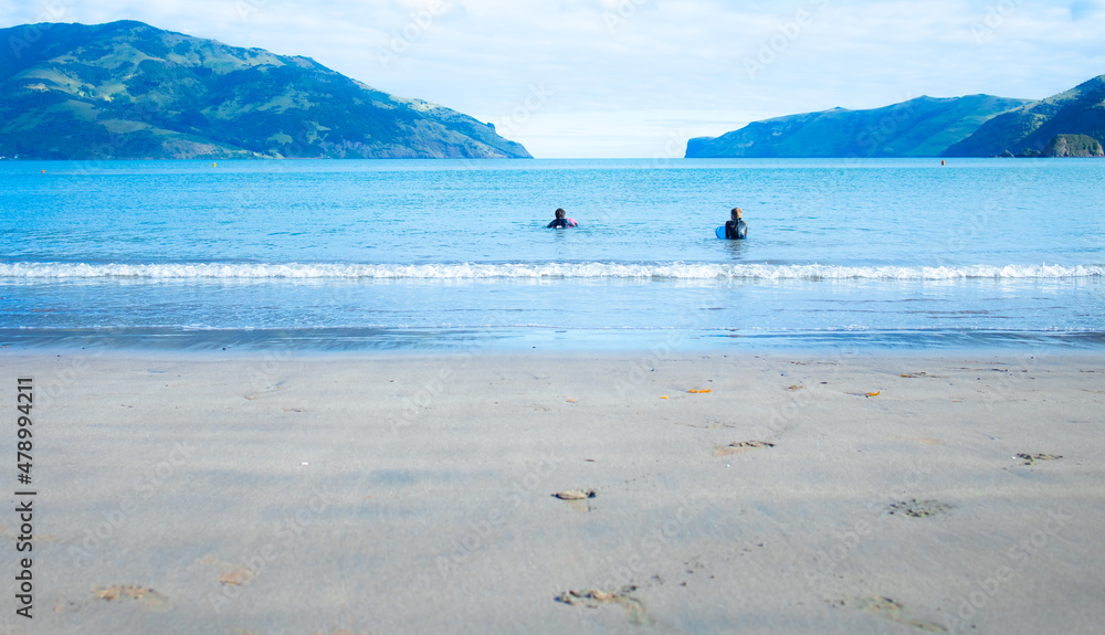 Two boys learning to surf on the New Zealand coast of the South Island in Wainui in the Summer.