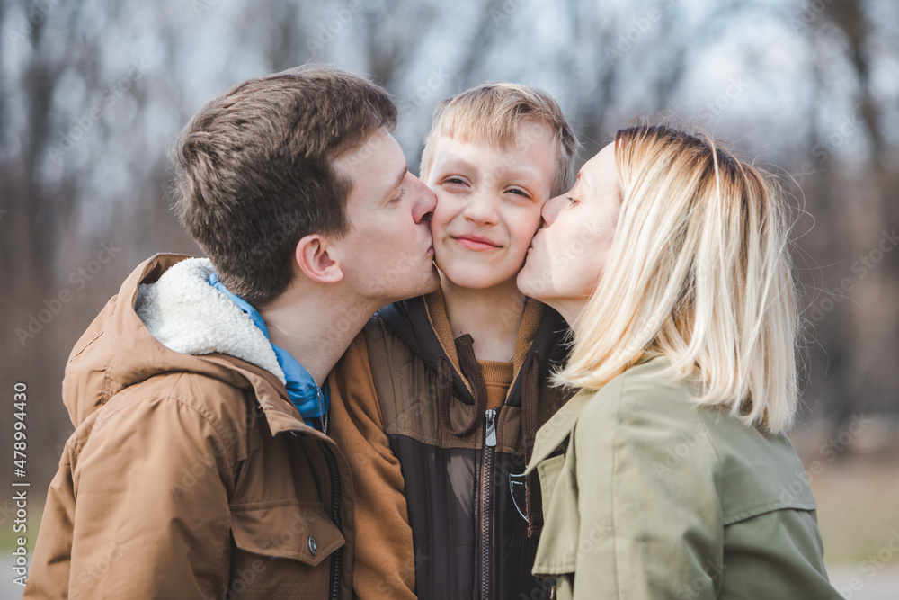 Fototapeta premium little boy son in the middle parent kissing in both cheeks