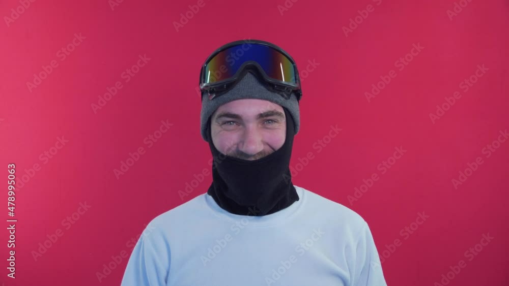 Positive Snowboarder Taking Off Snowboard Goggles, Smiling, Facial Expression Of Happiness And Joy, Everything Is Cool. Man in Snowboard Goggles in a White Jacket on a Red Background in the Studio Positive Snowboarder Taking Off Snowboard Goggles, Smiling, Facial Expression Of Happiness And Joy, Everything Is Cool. Man in Snowboard Goggles in a White Jacket on a Red Background in the Studio