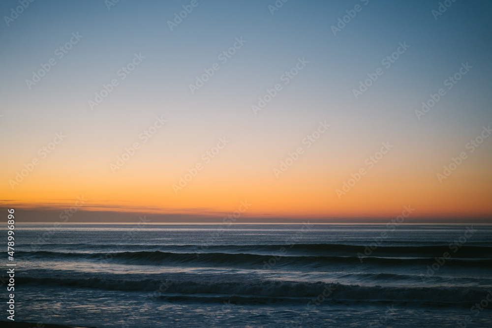 Small waves approaching the shore of Ilbarritz beach during a winter sunset