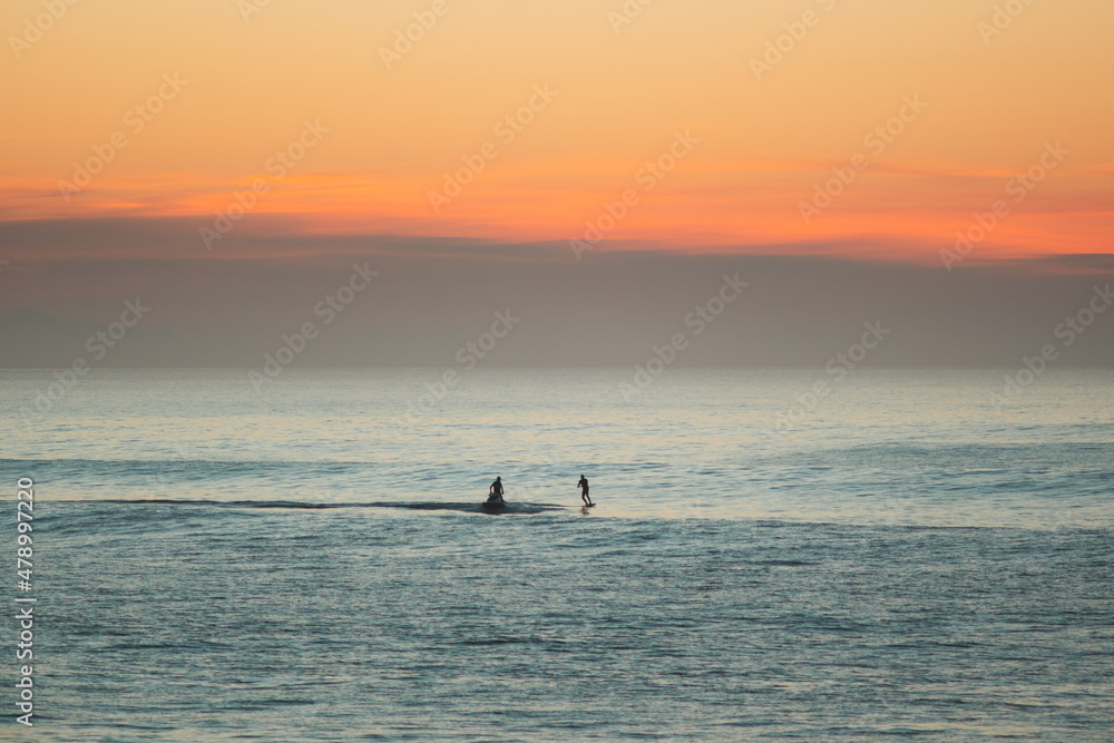 Fototapeta premium Jet ski towing a foil surfer during the sunset on atlantic ocean
