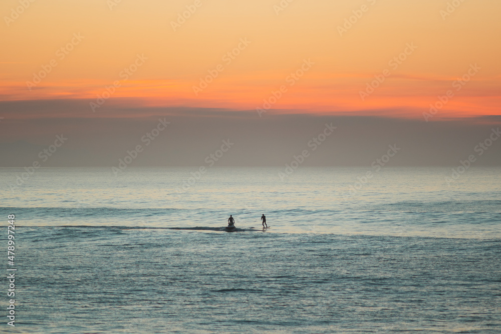 Fototapeta premium Jet ski towing a foil surfer during the sunset on atlantic ocean