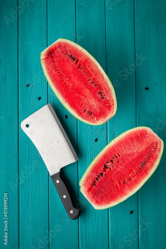 Watermelon sliced in a half with a backsword on the wooden turquoise background. Red juicy summer fruit berry photo