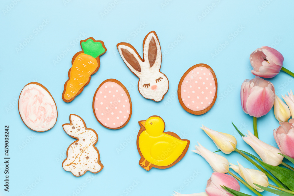 Glazed color gingerbread Easter figures - rabbit, chicken, egg, carrot  and tulips flowers on a blue background. Happy Easter. Top View