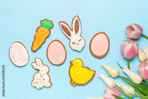 Glazed color gingerbread Easter figures - rabbit  chicken  egg  carrot  and tulips flowers on a blue background. Happy Easter. Top View