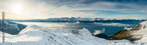 Snowcapped mountains surrounding Alpe Rogneda and Orobie Alps during a misty sunrise in autumn, Rhaetian Alps, Lombardy, Italy