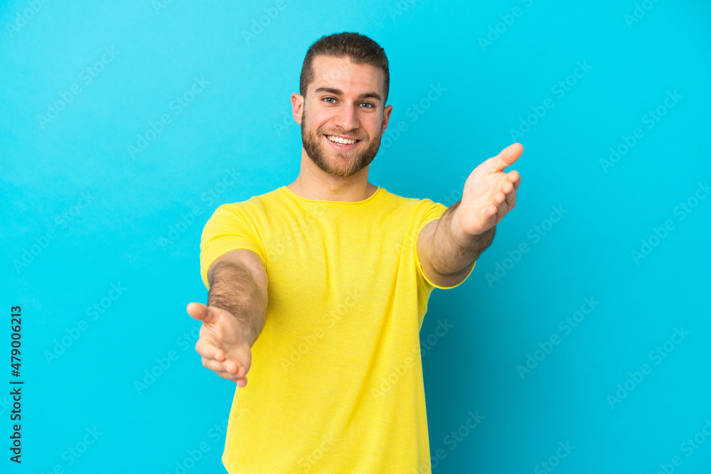 Young handsome caucasian man isolated on blue background presenting and inviting to come with hand Young handsome caucasian man isolated on blue background presenting and inviting to come with hand
