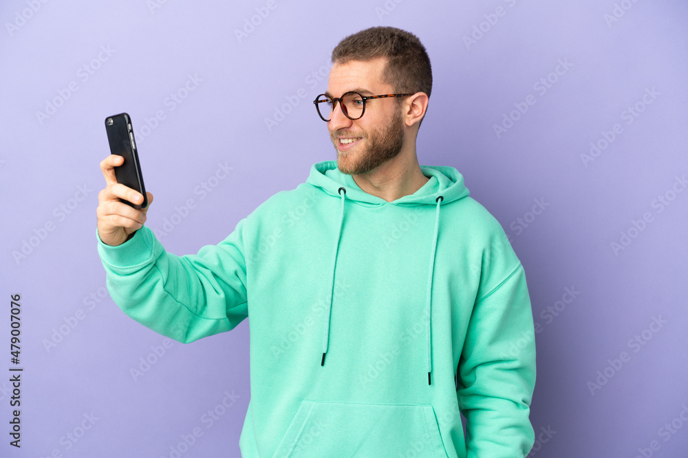 Young handsome caucasian man isolated on purple background making a selfie Young handsome caucasian man isolated on purple background making a selfie