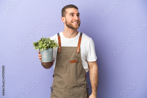 Gardener caucasian man holding a plant isolated on yellow background thinking an idea while looking up