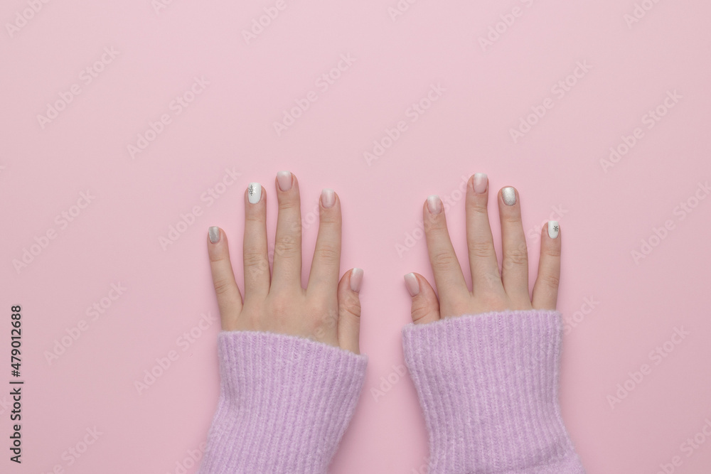 The hands of a girl in a warm sweater on a pink background. Manicure. Flat lay. The hands of a girl in a warm sweater on a pink background. Manicure. Flat lay.