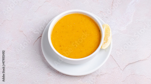 Turkish lentil soup with lemon slice isolated on white.