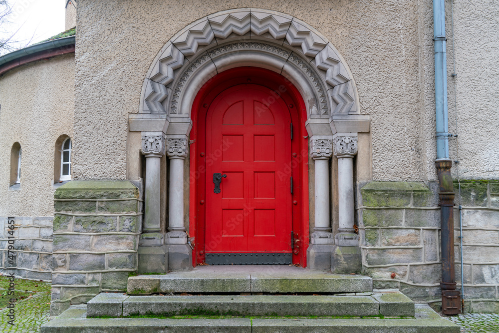 Red Door on an entrance in an old German church in a cloudy day.