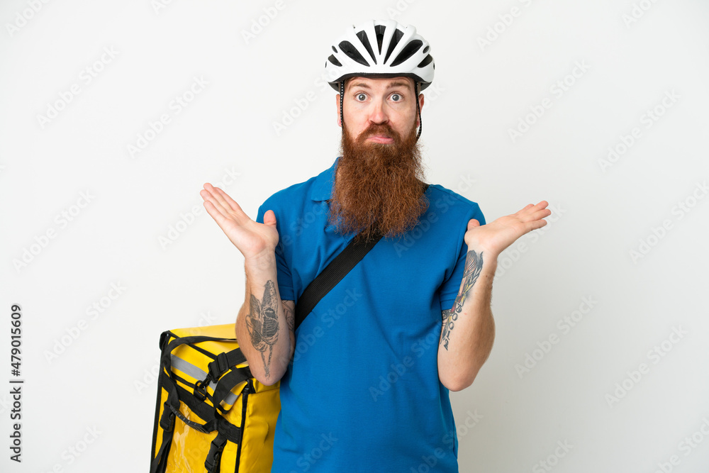 Young reddish caucasian man with thermal backpack isolate don white background having doubts while raising hands Young reddish caucasian man with thermal backpack isolate don white background having doubts while raising hands