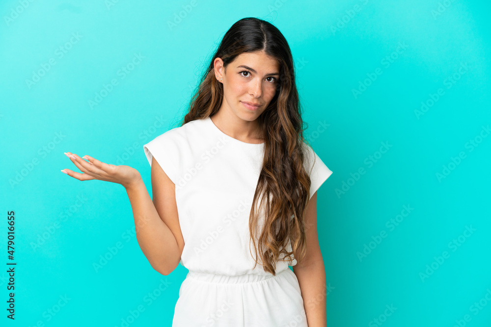 Young caucasian woman isolated on blue background making doubts gesture Young caucasian woman isolated on blue background making doubts gesture