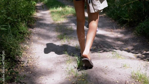 Dad and Son are Walking Along a Sandy Path in a Green Woods. Bare male and children feet in flip flop slowly step forward. Summertime. Shade from trees in the sunlight. Walk in fresh air. Relaxation.