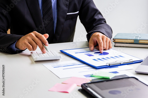 Male accountant calculates last quarter's earnings figures and points to documents to present, business man checking company income and finance documents, modern business man concept.