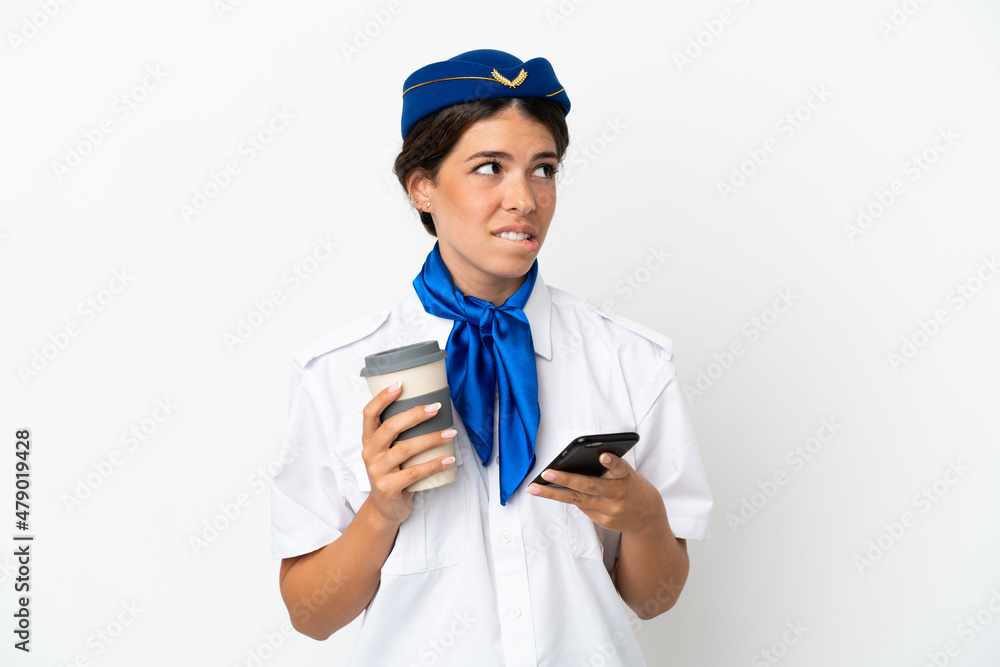 Airplane stewardess caucasian woman isolated on white background holding coffee to take away and a mobile while thinking something Airplane stewardess caucasian woman isolated on white background holding coffee to take away and a mobile while thinking something