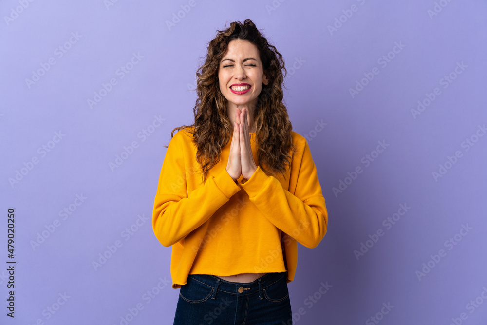 Young caucasian woman isolated on purple background keeps palm together. Person asks for something Young caucasian woman isolated on purple background keeps palm together. Person asks for something