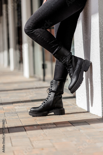 A slender woman in black leather boots, black trousers. Collection of shoes for women