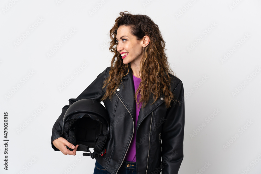 Young caucasian woman holding a motorcycle helmet looking to the side and smiling Young caucasian woman holding a motorcycle helmet looking to the side and smiling
