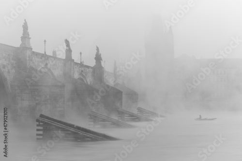 An amazing autumn atmosphere, cloudy, foggy and wet. Prague's famous landmark, river and one of many churches in the background. © janstria