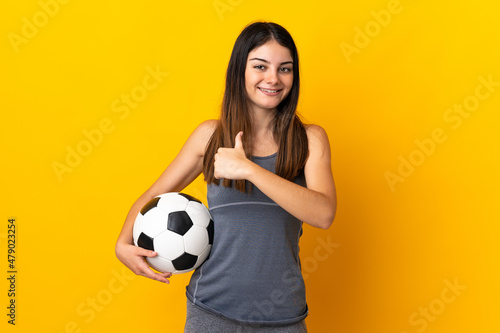 Young football player woman isolated on yellow background proud and self-satisfied © luismolinero
