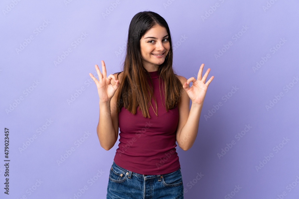 Young caucasian woman isolated on purple background showing ok sign with two hands Young caucasian woman isolated on purple background showing ok sign with two hands