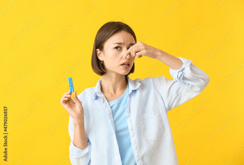 Ill young woman with clothespin on color background. Stuffy nose concept Ill young woman with clothespin on color background. Stuffy nose concept