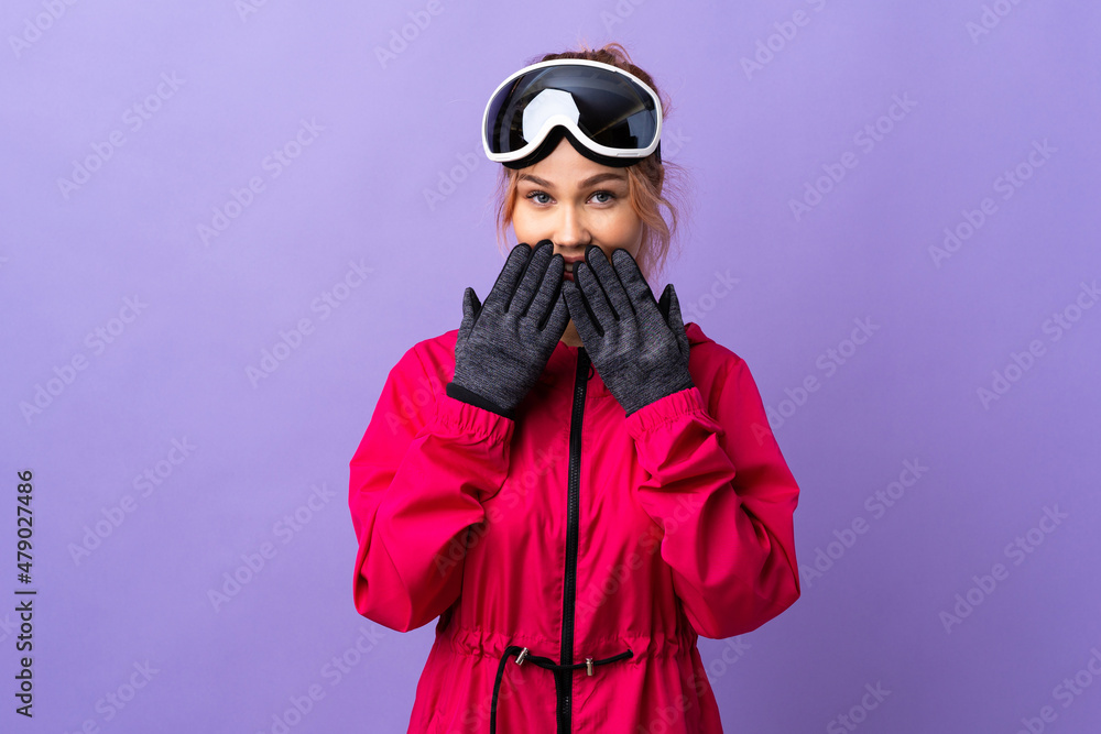 Skier teenager girl with snowboarding glasses over isolated purple background happy and smiling covering mouth with hands Skier teenager girl with snowboarding glasses over isolated purple background happy and smiling covering mouth with hands