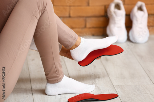 Sporty woman fitting red orthopedic insole at home