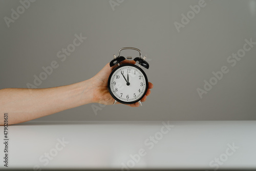 Hand holding black alarm clock