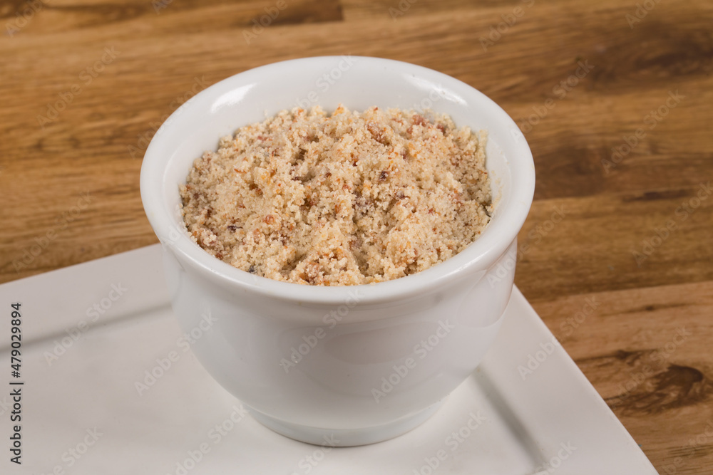 Brazilian Farofa. Manioc Flour into a white bowl on wooden background. Brazilian Farofa. Manioc Flour into a white bowl on wooden background.
