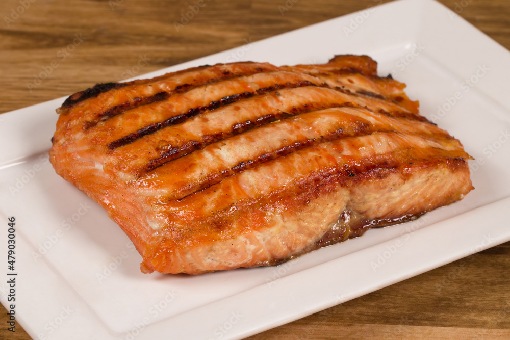 Grilled salmon fillet served on a white plate. Grilled salmon fillet served on a white plate.