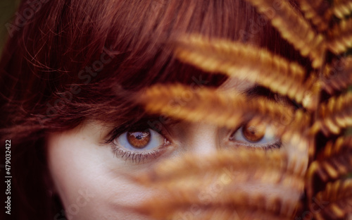 Creative red head portrait, close up golden and brown eyes, fern.