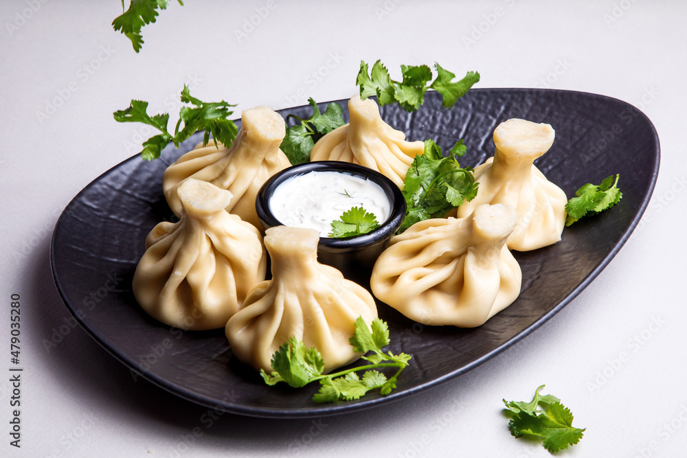 khinkali with white sauce on a dark plate on a light background khinkali with white sauce on a dark plate on a light background