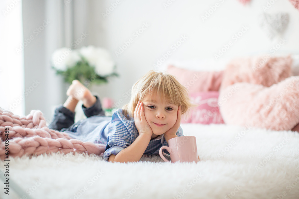 Cute toddler blond child with shirt, sitting on the bed with Valentine decoration